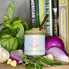 Load image into Gallery viewer, Jar of Mediterranean Herbed Full Circle Ghee arranged with onions, garlic, and fresh herbs.